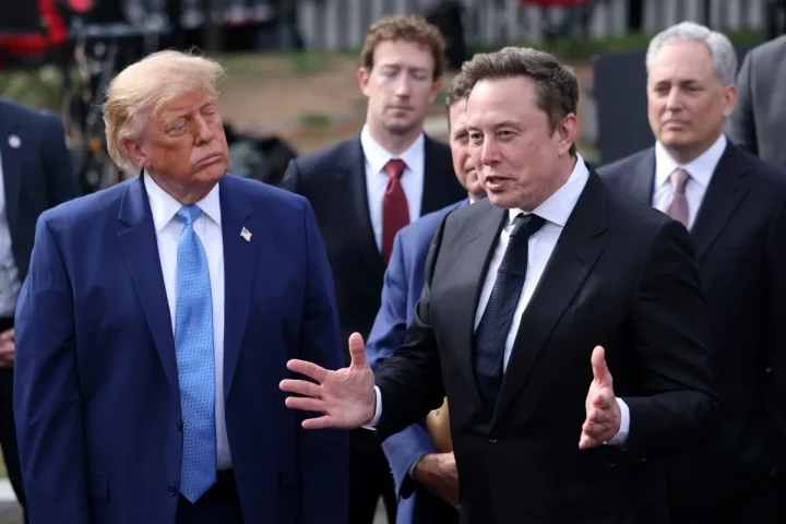 Donald Trump ve Elon Musk, başka kişilerin de bulunduğu bir açık hava etkinliğinde yan yana