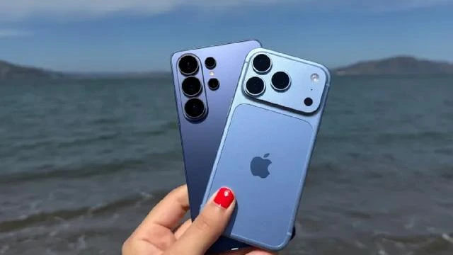 Deniz kıyısında elde tutulan iki akıllı telefon