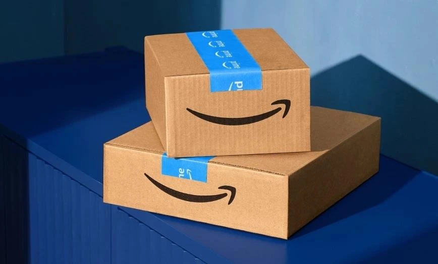 Mavi zemin üzerinde üst üste duran iki Amazon kargo kutusu
