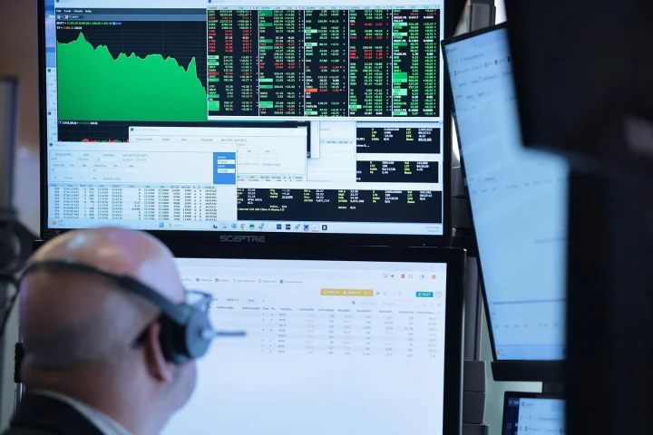 Bir finans piyasası çalışanı, grafik ve piyasa verilerinin yer aldığı monitörlerin önünde çalışıyor
