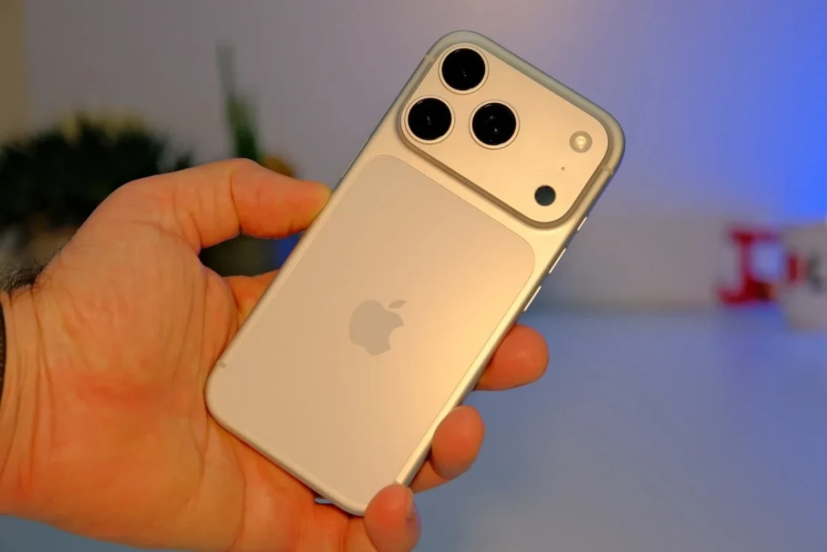 Bir kişinin elinde tuttuğu üç arka kamerali açık renkli Apple telefonu