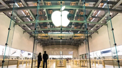 Cam cepheli bir Apple mağazasının girişinde ışıklı Apple logosu
