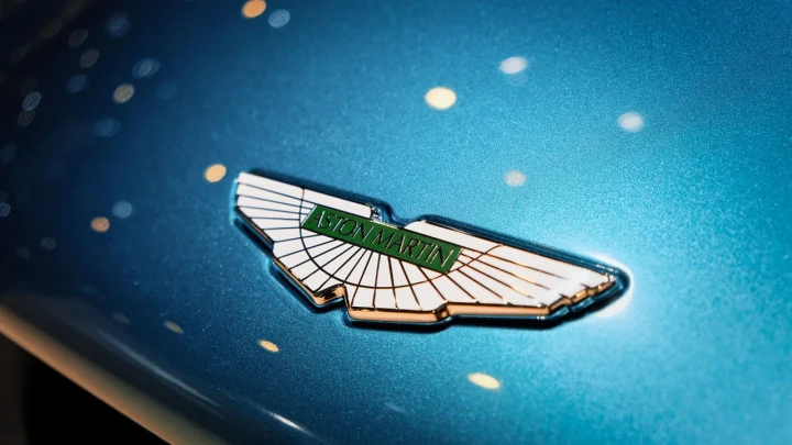 Mavi bir otomobilin üzerinde Aston Martin kanatlı amblemi