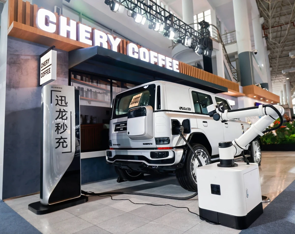 Chery Coffee alanında beyaz bir aracın yanında duran robotik şarj kolu