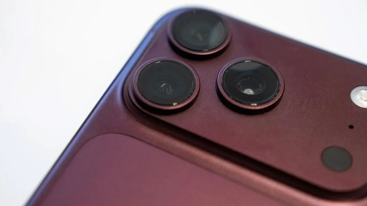 Bordo renkli bir akıllı telefonun arka yüzündeki üçlü kamera modülünün yakın plan görüntüsü