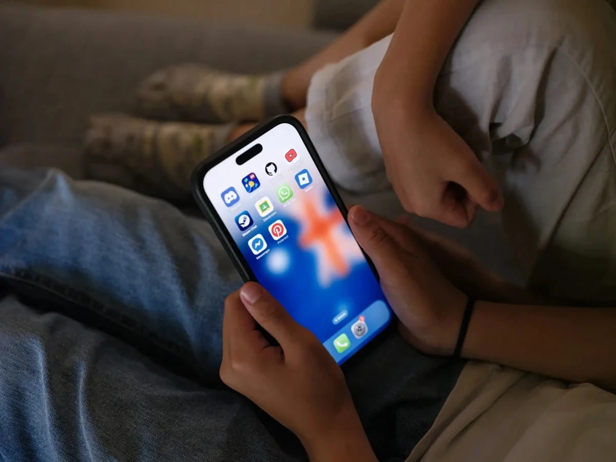 Bir çocuk ve yetişkinin elinde sosyal medya uygulamalarının bulunduğu akıllı telefon