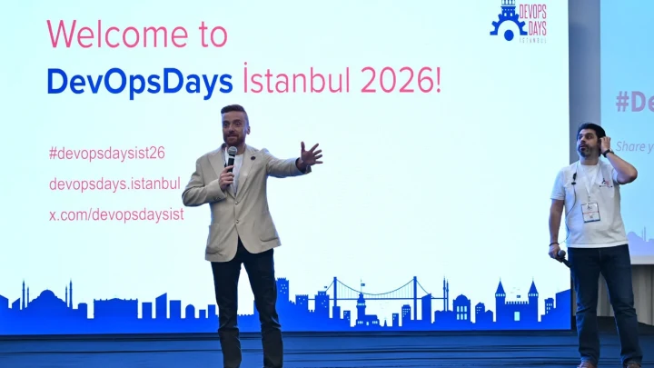 DevOpsDays İstanbul 2026 açılışında iki konuşmacı sahnede katılımcılara sesleniyor