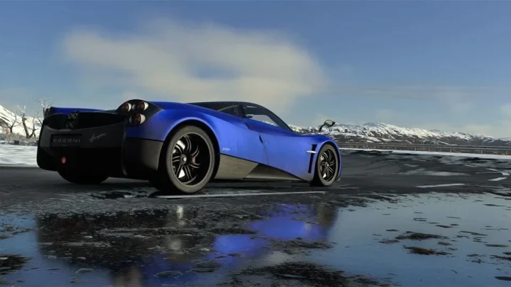 Driveclub oyunundan, mavi bir otomobilin karlı dağların önündeki ıslak zeminde ilerlediği sahne