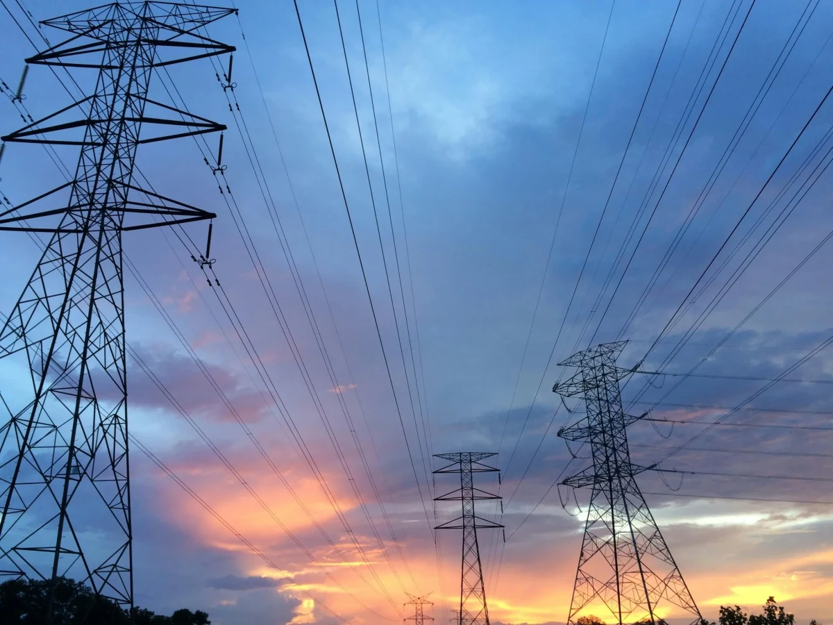 Gün batımında gökyüzüne uzanan elektrik iletim hatları ve yüksek gerilim direkleri