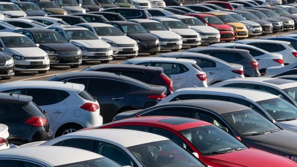 Açık bir otoparkta sıralar hâlinde park edilmiş çeşitli otomobiller