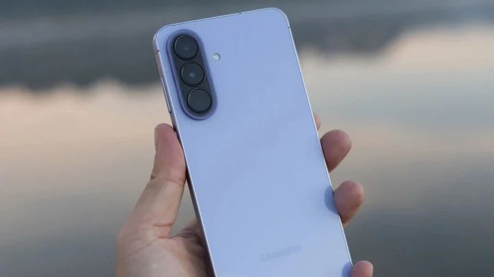 Açık mavi renkli, arka tarafında üç kamera bulunan bir Samsung akıllı telefon elde tutuluyor.