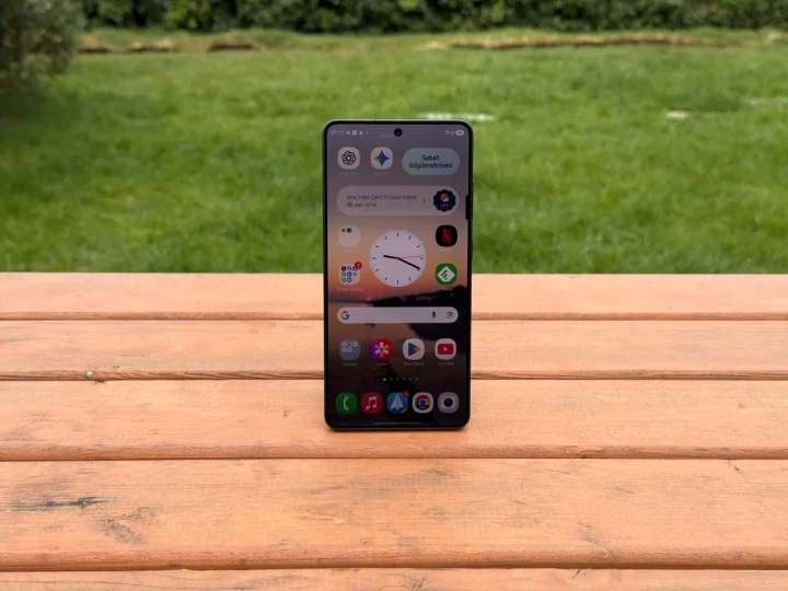 Ahşap bir yüzey üzerinde dik konumda duran, ekranı açık Samsung akıllı telefon
