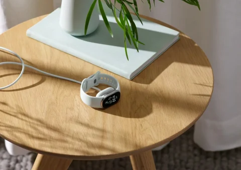 Beyaz kayışlı Google Fitbit Edge, ahşap bir masa üzerinde duruyor