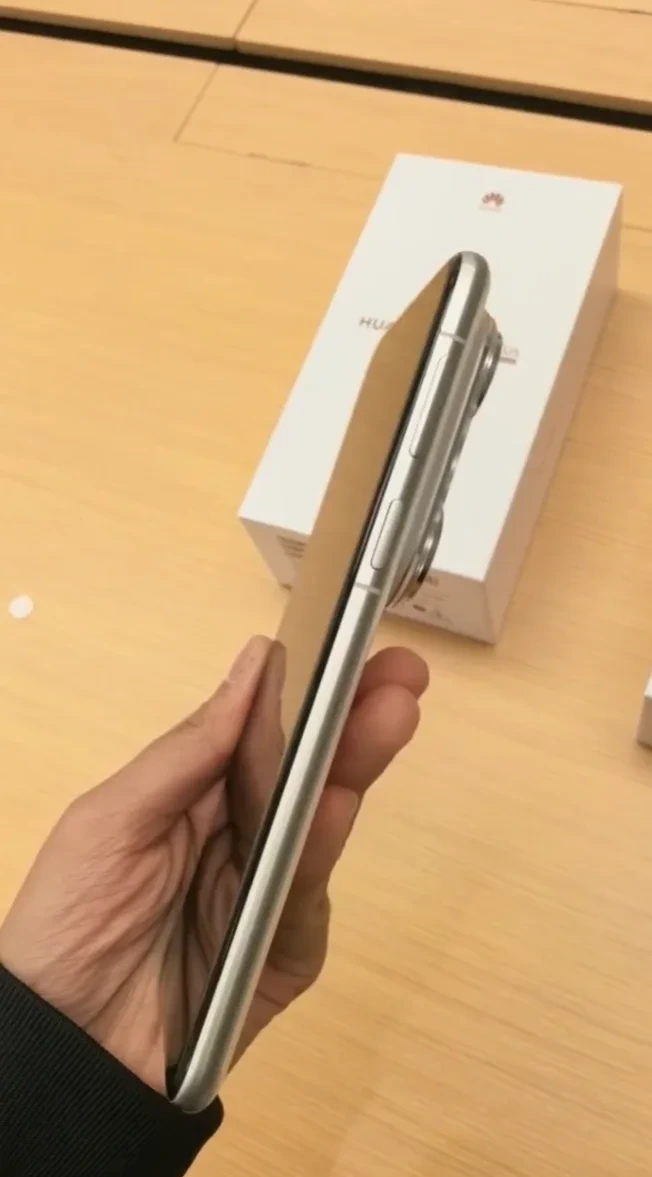 Bir kişinin elinde tuttuğu Huawei telefonu, arka planda telefon kutusu