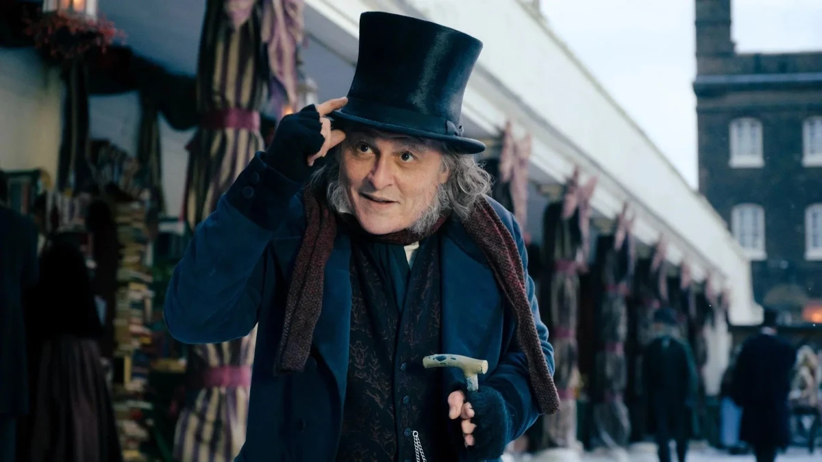 Johnny Depp, Ebenezer Scrooge kostümüyle silindir şapkasını tutarken