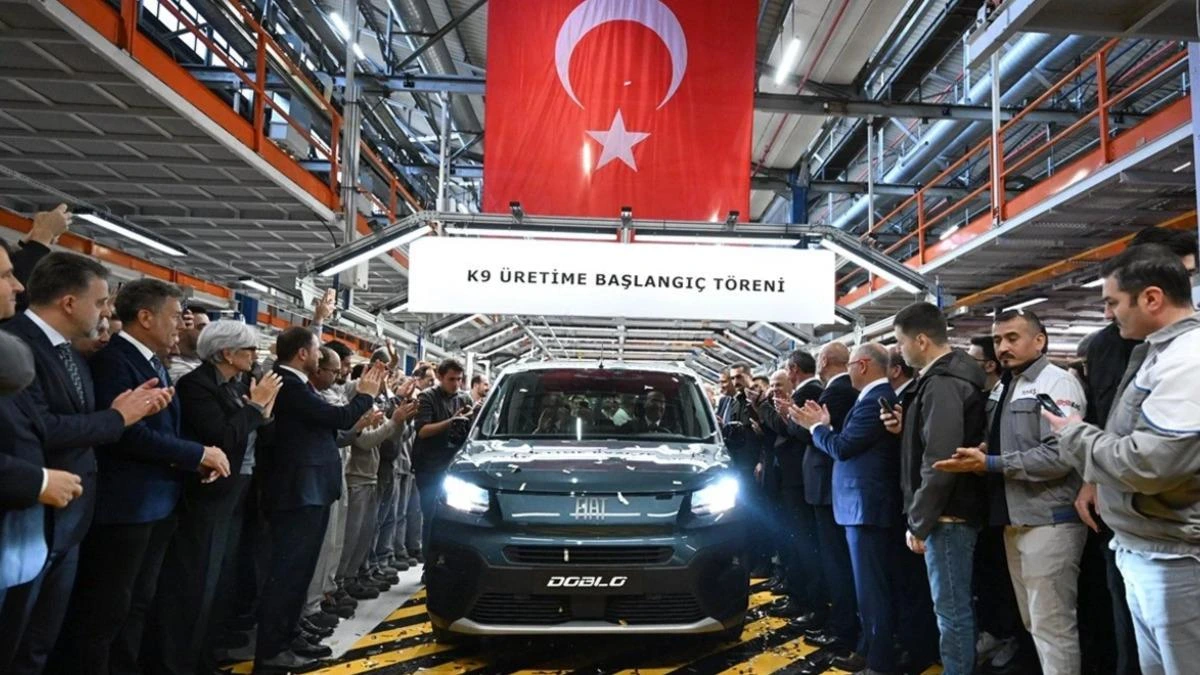 Türk bayrağının altında, üretim hattında ışıkları yanan Fiat Doblo’nun iki yanında töreni izleyenler alkış tutuyor.
