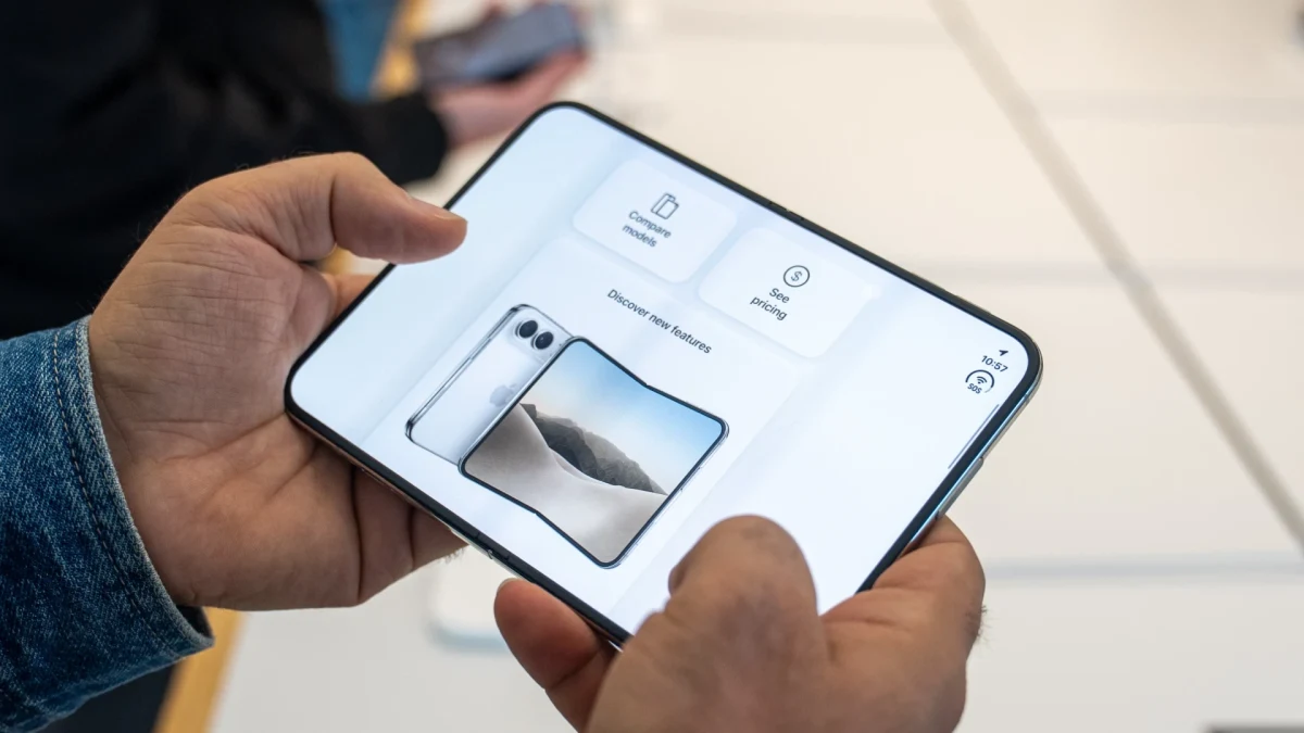 Ekranında ürün görseli bulunan katlanabilir telefonu elinde tutan kişi