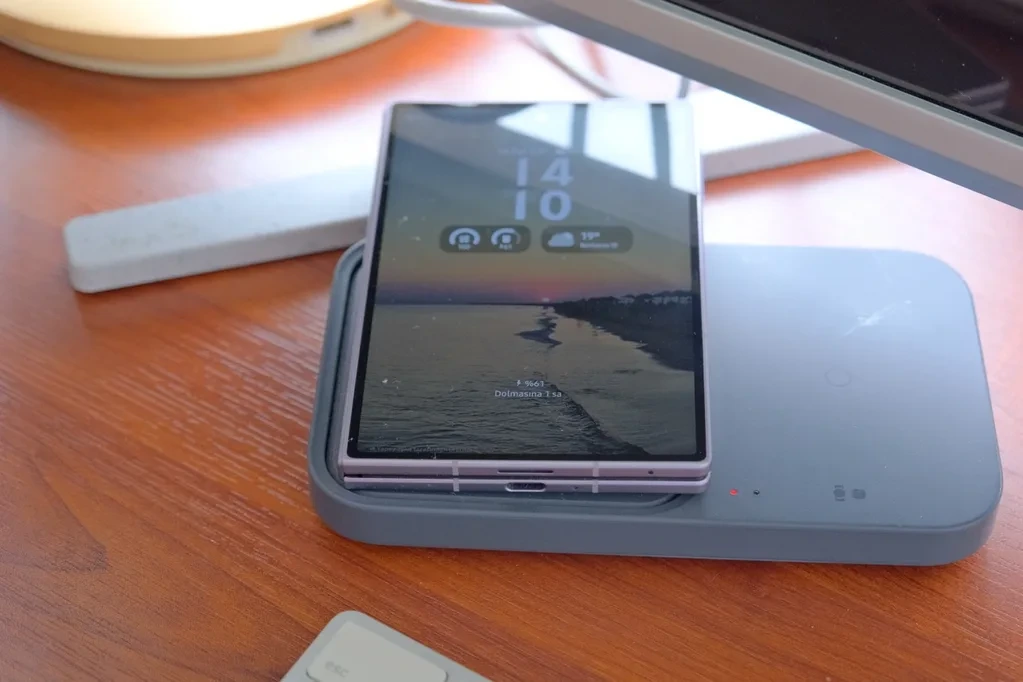 Ahşap masa üzerindeki kablosuz şarj standında kapalı durumdaki katlanabilir telefon