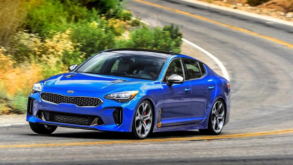 Virajlı yolda ilerleyen mavi Kia Stinger sedan