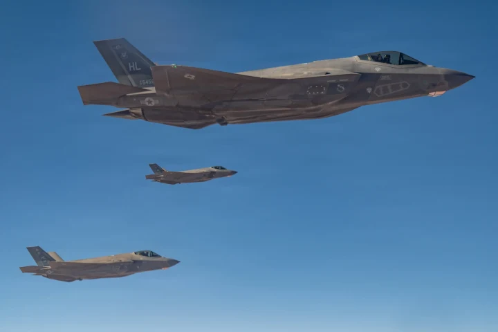 Mavi gökyüzünde uçan üç F-35 savaş uçağı