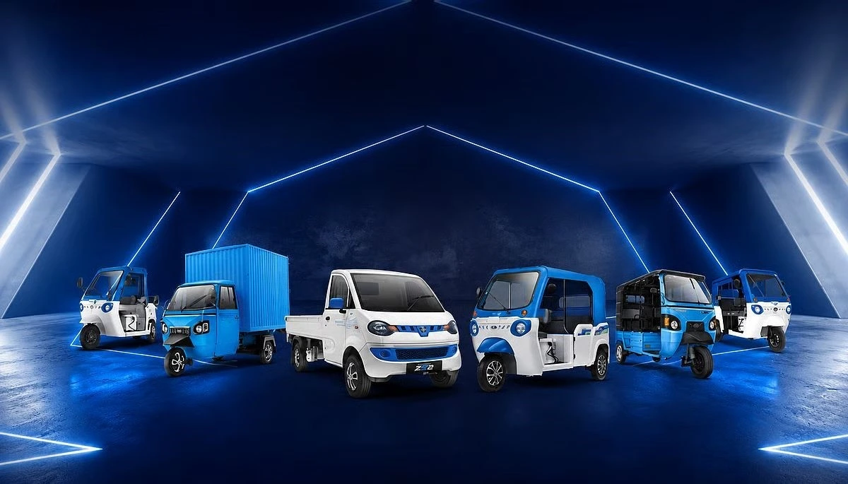 Mavi ışıklarla aydınlatılmış bir alanda sergilenen elektrikli tuk-tuklar ve ticari araçlar