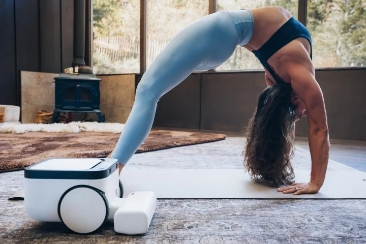 Ev ortamında robot süpürgenin yanında egzersiz yapan bir kişi