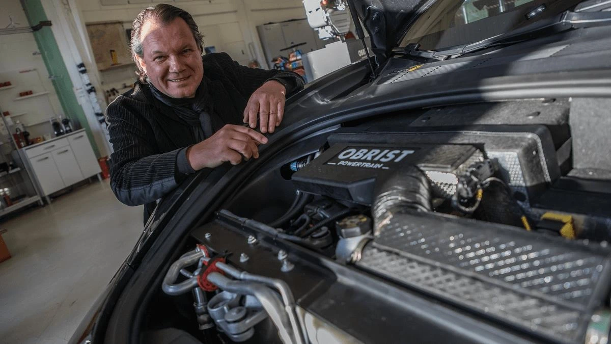 Obrist yazılı sistemi inceleyen bir kişi ve açık Tesla ön bagajı
