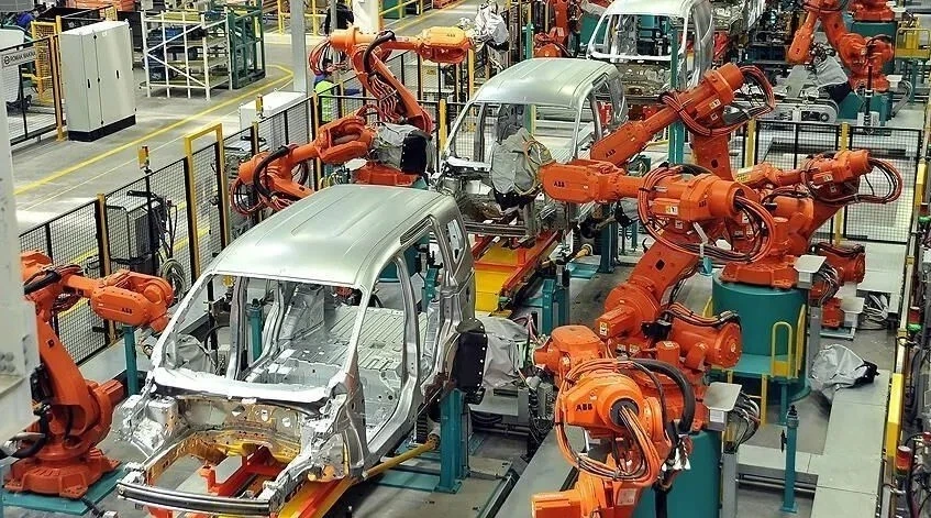 Otomobil fabrikasında araç gövdeleri üzerinde çalışan endüstriyel robotlar