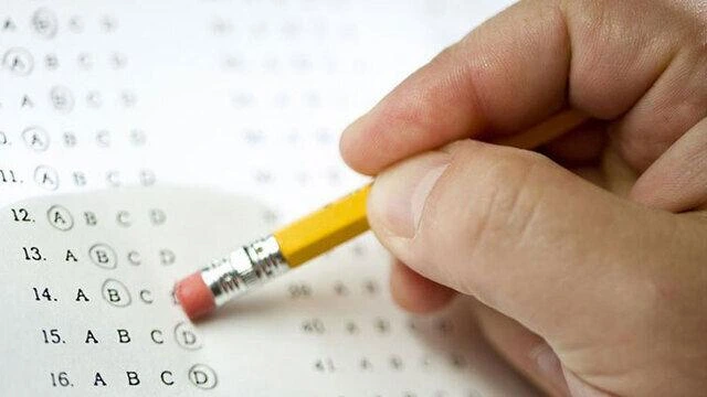 Bir el, çoktan seçmeli sınav kâğıdındaki işareti silgiyle düzeltiyor