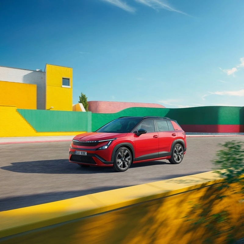 Kırmızı Skoda Epiq Sportline, renkli duvarların önünde yolda ilerlerken