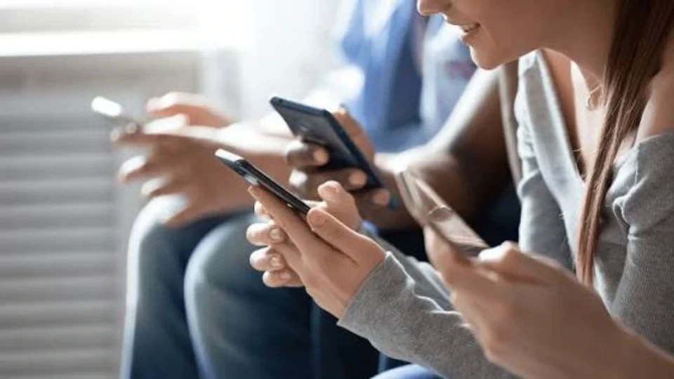 Yan yana oturan kişilerin akıllı telefonlarını kullandığı görüntü