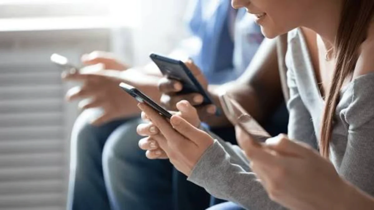 Yan yana oturan kişilerin akıllı telefonlarını kullandığı görüntü