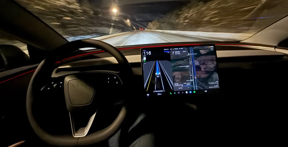 Tesla otomobilinin gece sürüşünde direksiyonu ve orta ekrandaki sürüş arayüzü