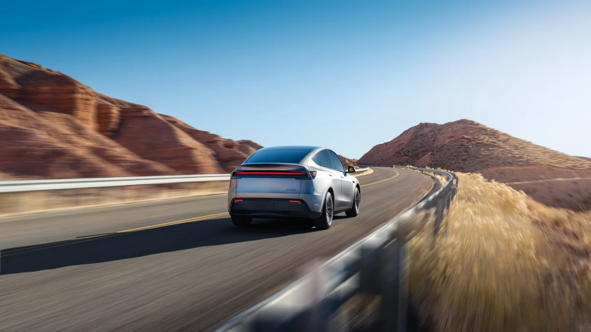 Dağlık bir yolda ilerleyen Tesla Model Y’nin arkadan görünümü