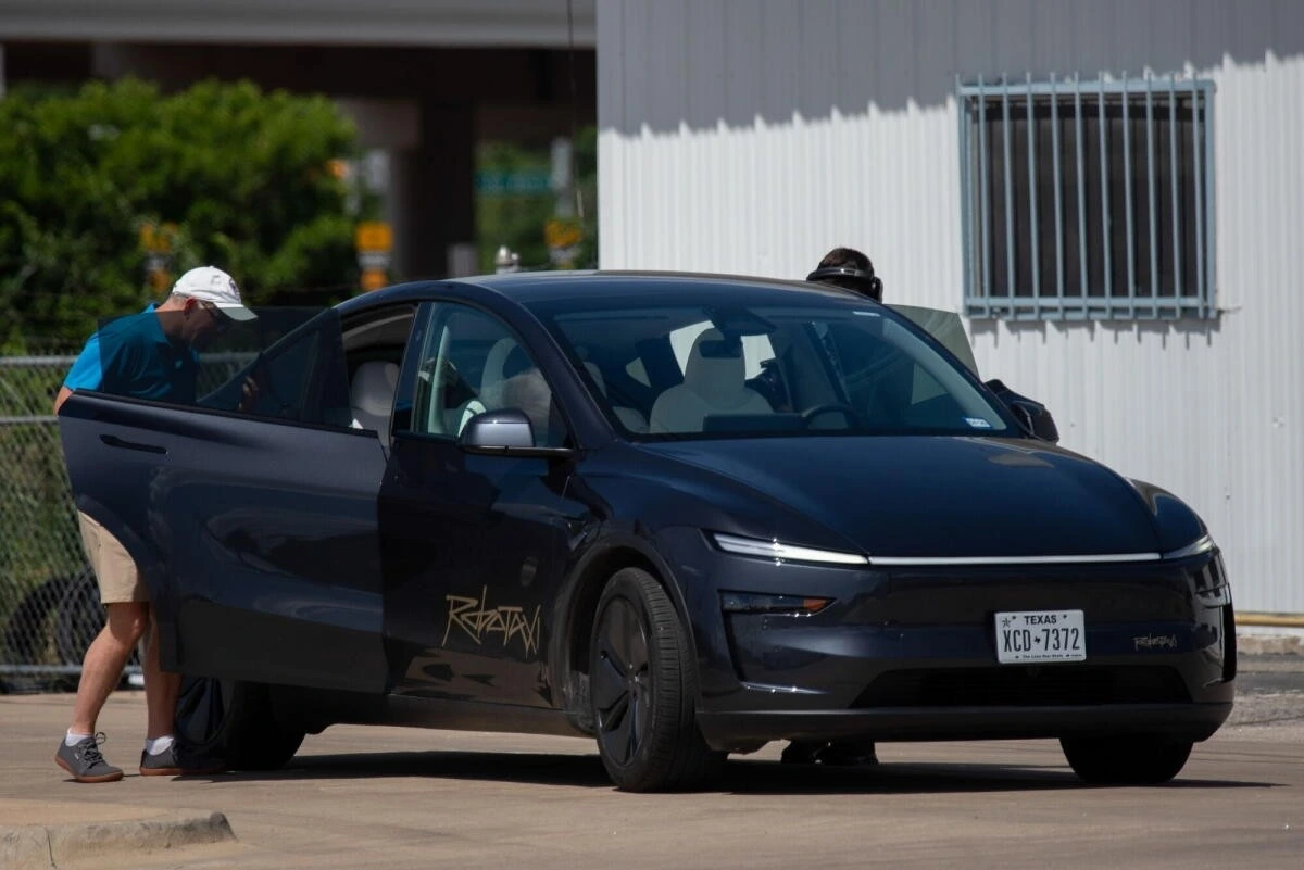 Açık kapısının yanında bir kişi bulunan Tesla otomobili