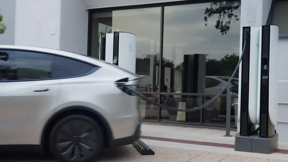 Tesla otomobili Supercharger istasyonunun yanında hareket ederken şarj kablosu bağlantısı ayrılıyor