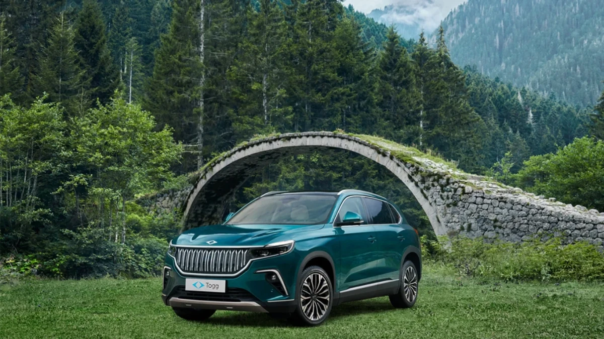 Taş köprünün önünde çimenlik alanda duran turkuaz Togg SUV