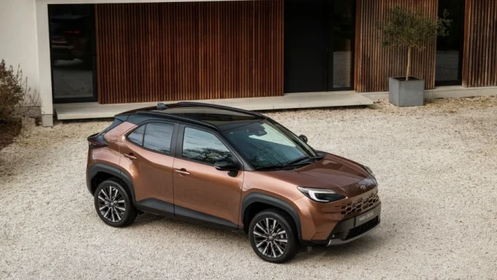 Aura Bronz renkli Toyota Yaris Cross Hybrid, bir binanın önünde park halinde