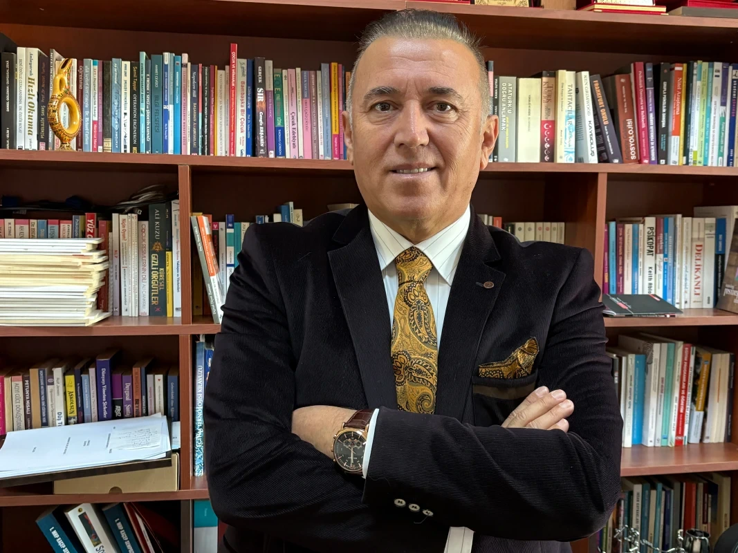 Prof. Dr. Tuncay Dilci kitaplık önünde kollarını kavuşturmuş halde