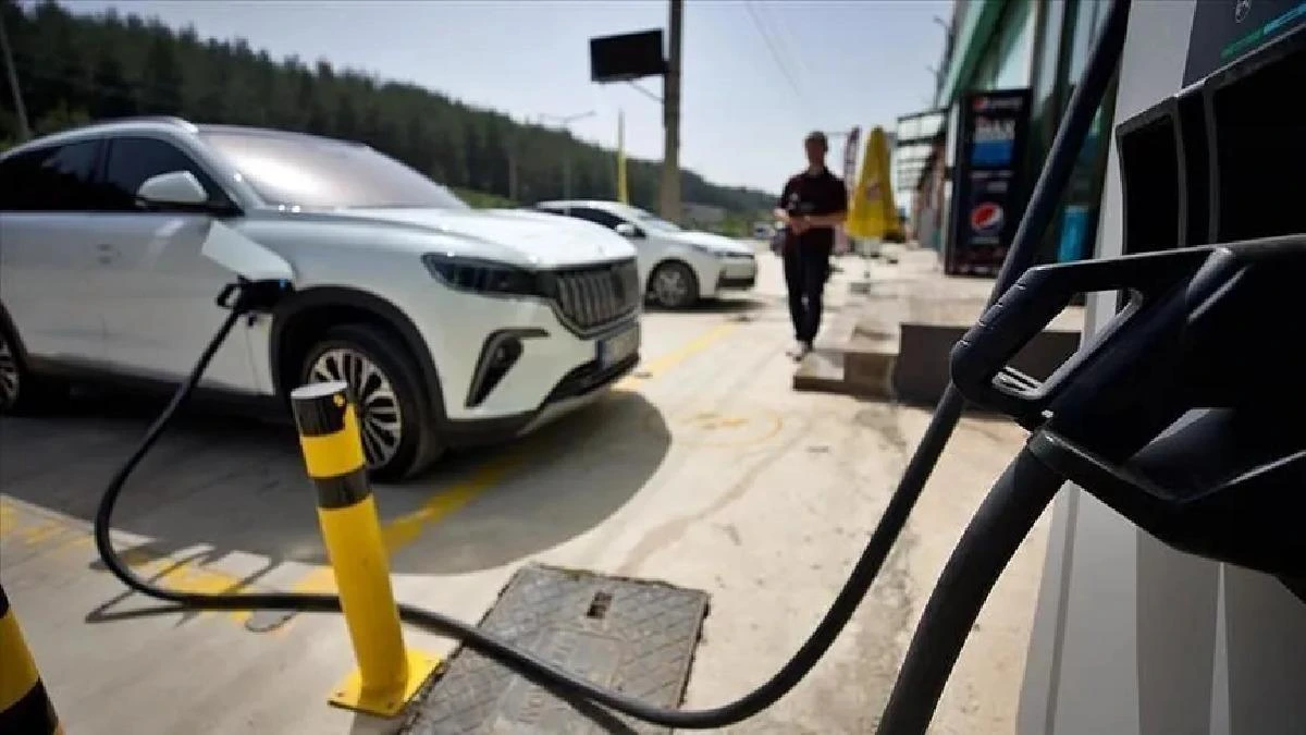 Şarj istasyonunda kabloyla şarj edilen beyaz elektrikli otomobil
