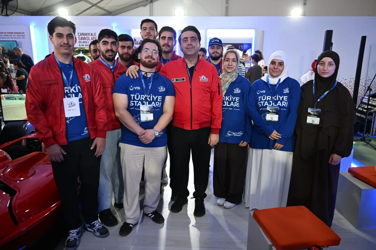 Türkiye Stajları yazılı yelekler giyen öğrenciler bir sergi alanında toplu fotoğraf çektiriyor