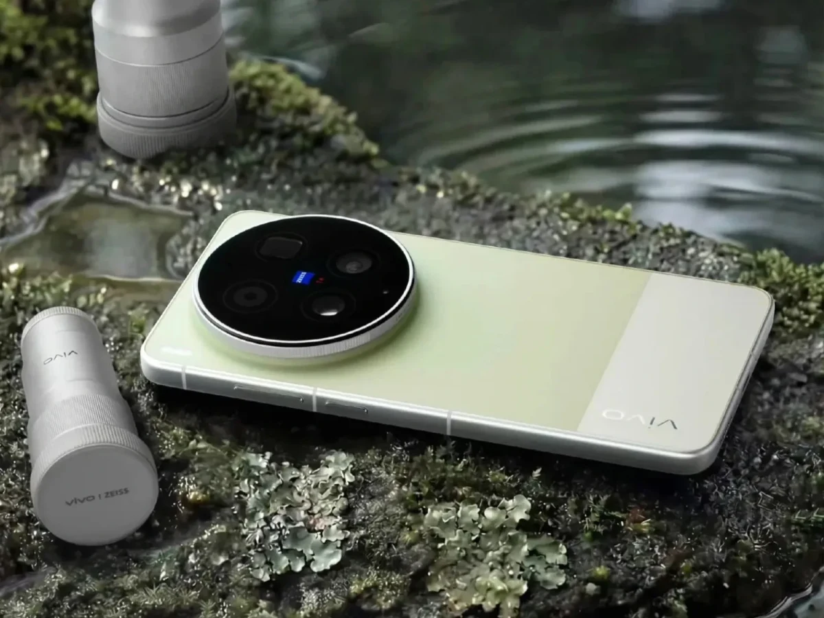 Su kenarındaki taşlı yüzey üzerinde duran, büyük dairesel kamera modülüne sahip açık renkli Vivo telefon
