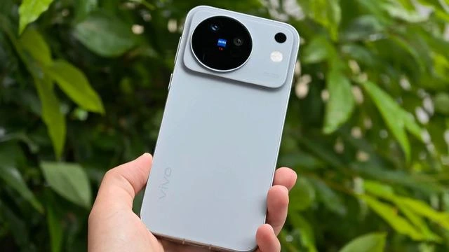 Bir kişinin elinde tuttuğu, arka yüzünde büyük dairesel kamera modülü bulunan açık renkli vivo telefonu