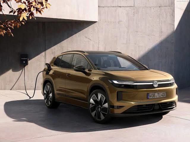 Beton duvar önünde şarj ünitesine bağlı bronz renkli Volkswagen SUV