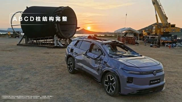 Test sonrası ezilmiş gövdesi görülen Volkswagen ID. AURA T6, büyük silindirik tamburun önünde duruyor.