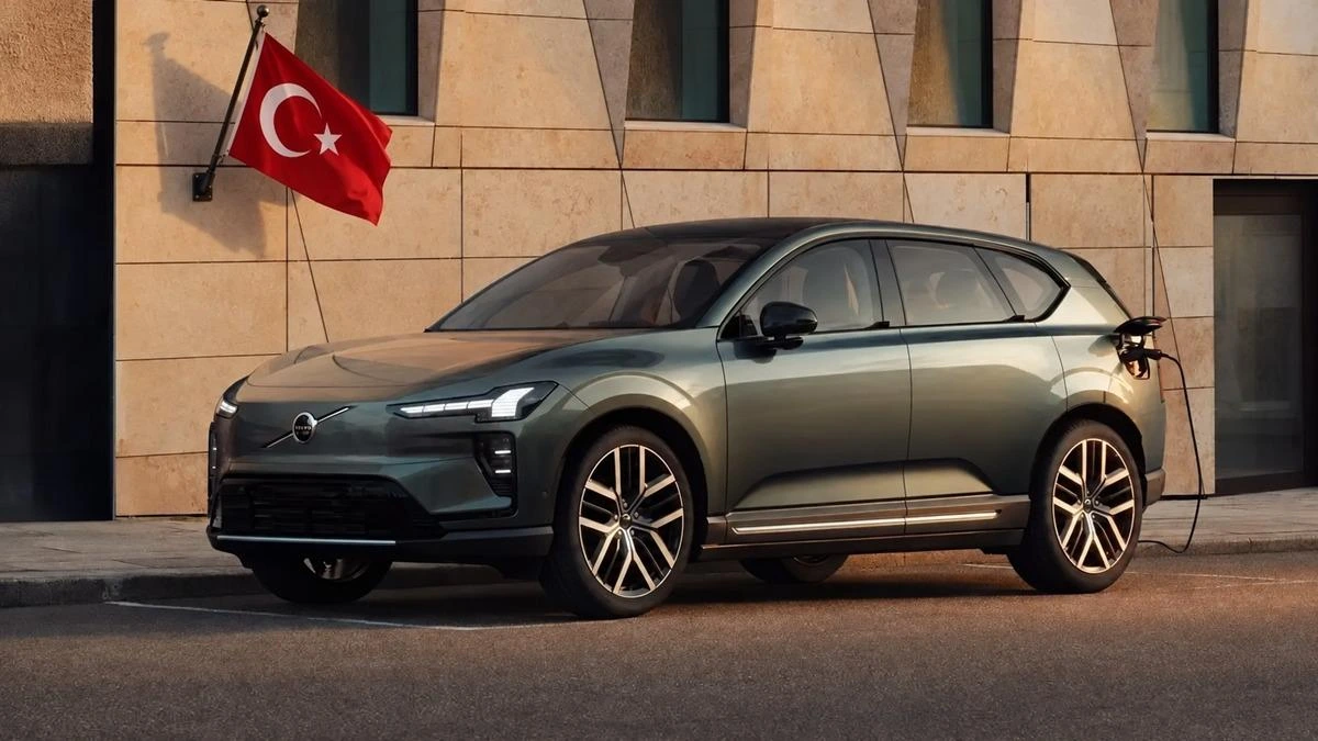 Taş kaplı bir binanın önünde park etmiş gri Volvo EX60; arka planda Türkiye bayrağı görülüyor