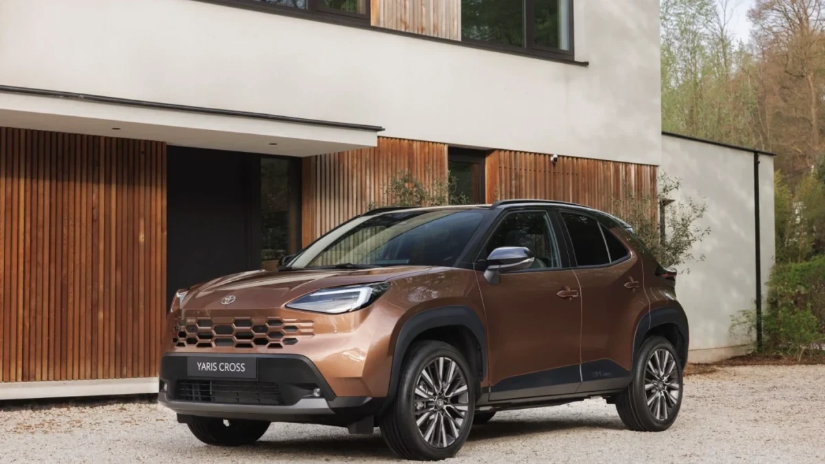 Toyota Yaris Cross Hybrid, binanın önünde önden ve yandan görünümle park halinde