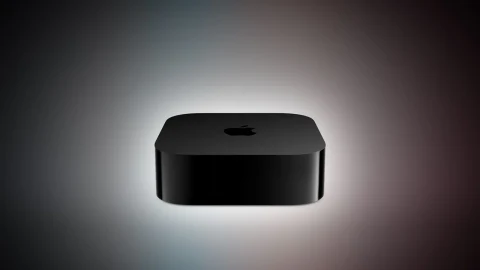 Koyu renkli Apple TV cihazı, karanlık arka plan önünde görüntüleniyor