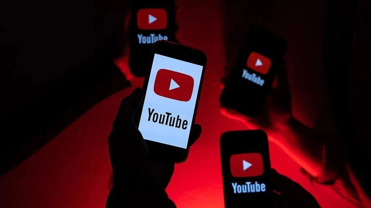 Kırmızı ışık altında YouTube logosu gösteren akıllı telefonlar