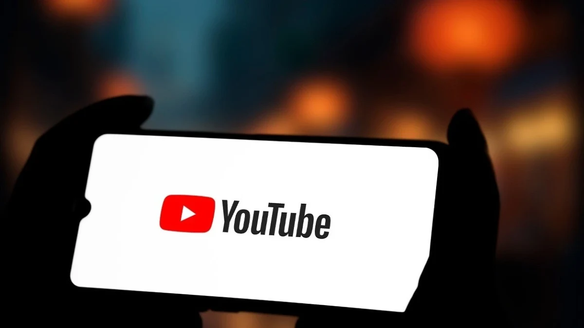 Ekranında YouTube logosu bulunan akıllı telefonu tutan kişinin silüeti